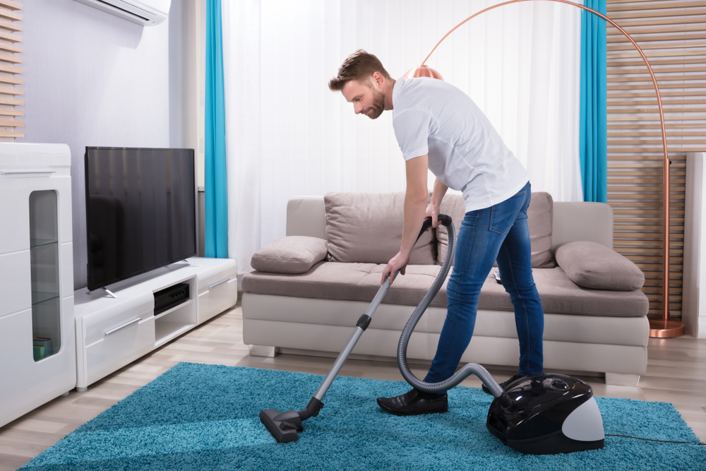 Person vacuuming carpet in Lagos Nigerian home using affordable vacuum cleaner
